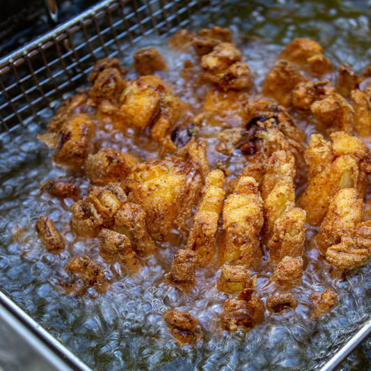 Onion being fried in an outdoor fry basket