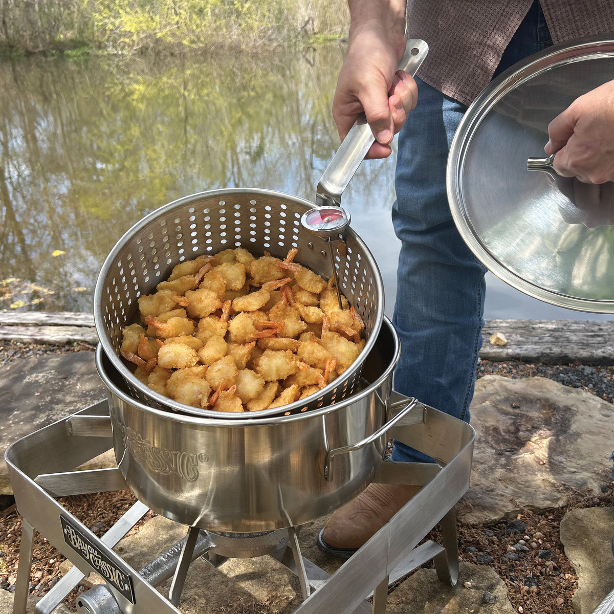 Person frying shrimp outside with a stainless fry pot and cooker
