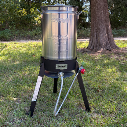A stainless steel turkey fryer pot on a steel  cooker in an outdoor setting.