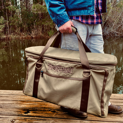 Man holding gear bag outside next to a body of water