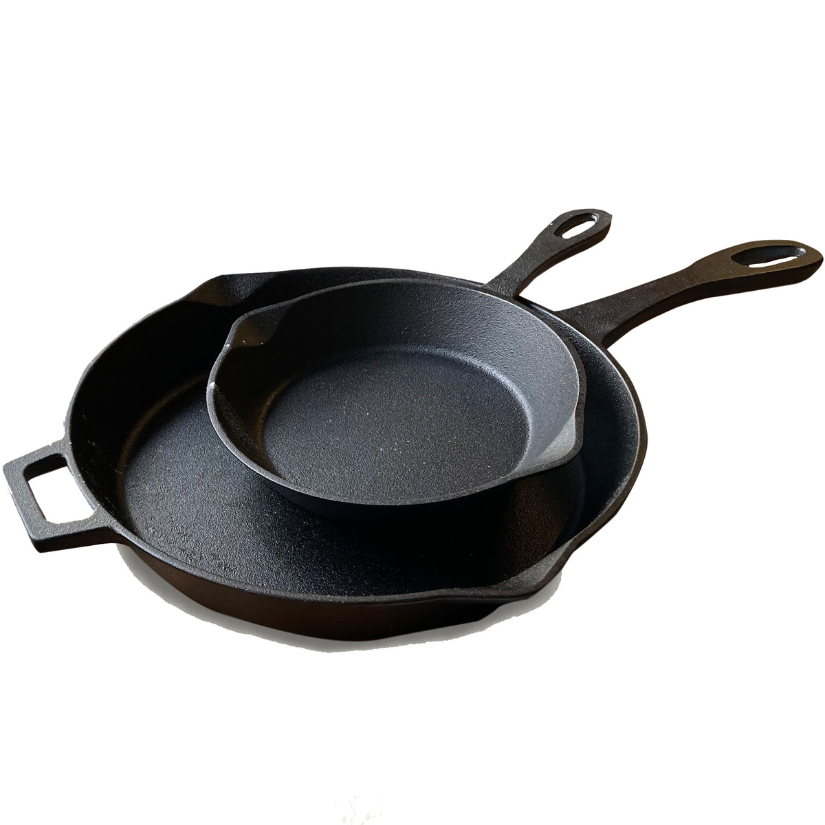 A set of two black cast iron skillets, one larger than the other, with pour spouts and handles on a white background.