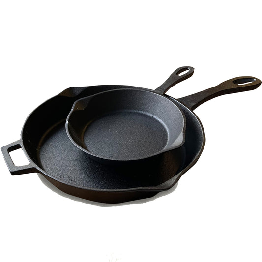 A set of two black cast iron skillets, one larger than the other, with pour spouts and handles on a white background.