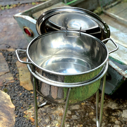 Stainless kettle with stand showing how the lid can hang on the side in an outdoor setting