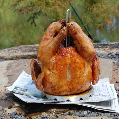 Fried turkey on a poultry rack draining on newspaper in an outdoor setting